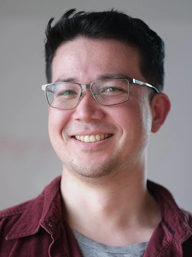 Eric Jing Mockler, smiling in glasses and a burgundy shirt