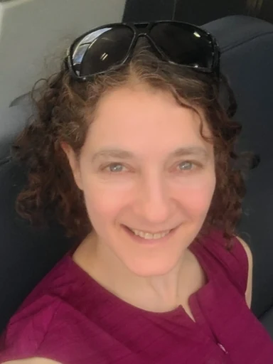 Karen Sachs, smiling, with sunglasses pushed up into her curly hair